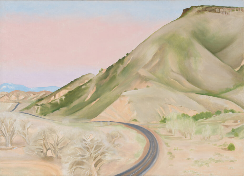 A winding road enters the scene from the base of the canvas in the center. It curves to the right before weaving off into the distance to the left. A large, light-colored mesa rises from the right side of the work, its hills sloping down towards the left. Several trees dot the landscape in the foreground, and the sky appears hazy.