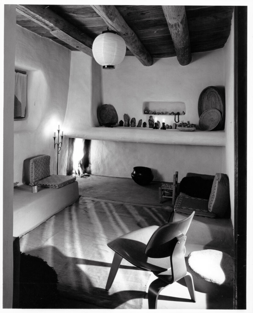 A photograph of Georgia O'Keeffe's home and studio. In the background there are banco shelves built into the adobe with various tschockes placed on the shelves.