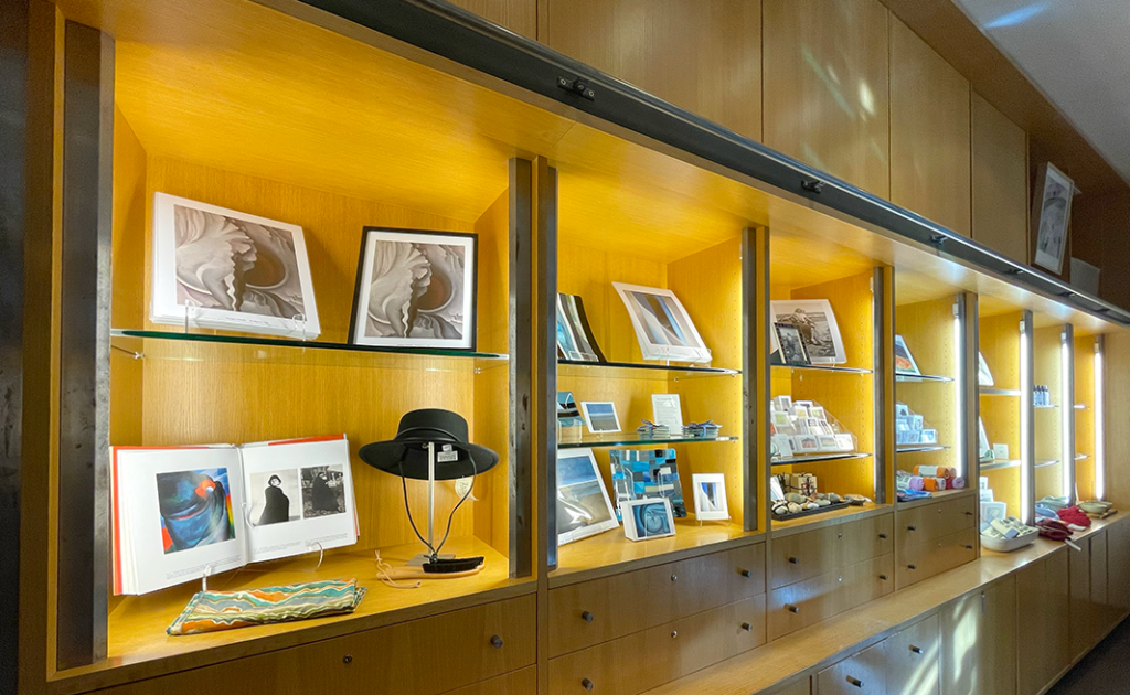 Image of wooden shelves in the Museum Store with objects for sale on them like a Gaucho Hat, scarves and art prints