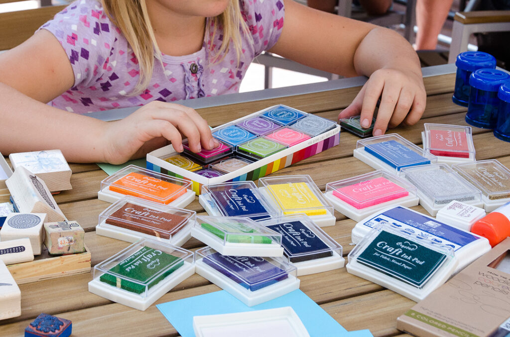 Image of a young person's hands with various stamp ink pads in different colors on a table