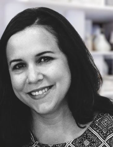 Black and white photograph of a person with dark hair smiling at the camera. 