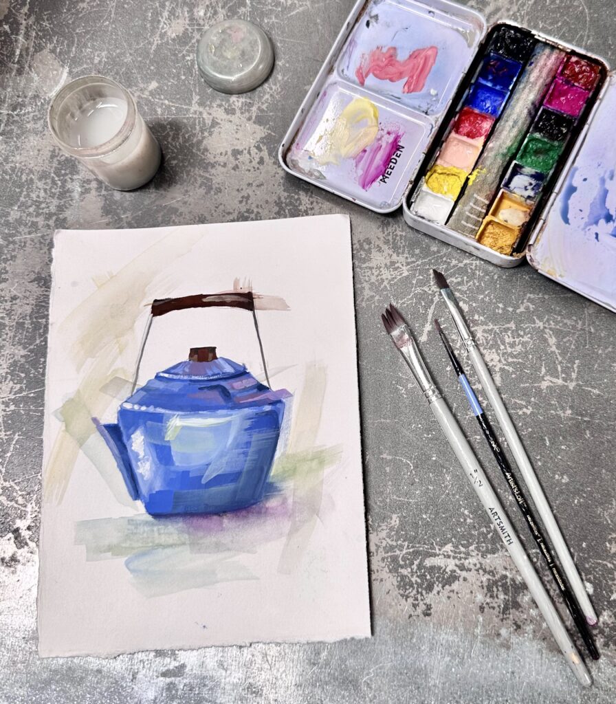 A small painting of a blue kettle on a small piece of paper. Near it are paintbrushes and a watercolor palette.