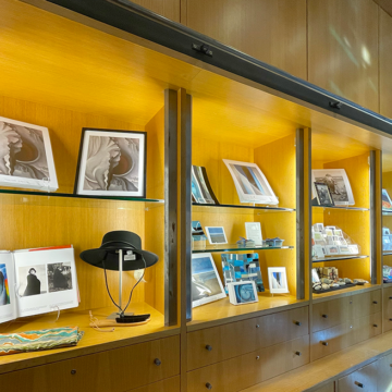 Image of wooden shelves in the Museum Store with objects for sale on them like a Gaucho Hat, scarves and art prints
