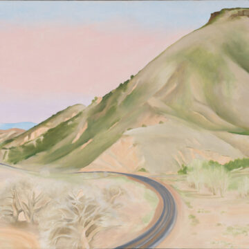 A winding road enters the scene from the base of the canvas in the center. It curves to the right before weaving off into the distance to the left. A large, light-colored mesa rises from the right side of the work, its hills sloping down towards the left. Several trees dot the landscape in the foreground, and the sky appears hazy.