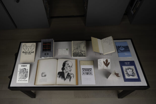 A case with books on art, letters, a sketch of O'Keeffe, postcards, and other archival items.