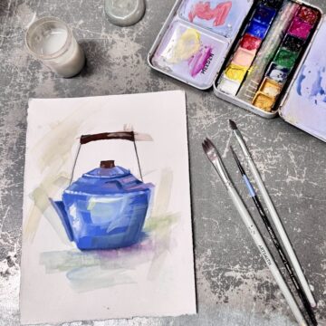 A small painting of a blue kettle on a small piece of paper. Near it are paintbrushes and a watercolor palette.